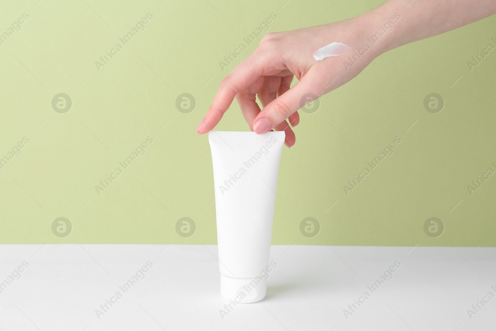 Photo of Woman with tube of cream on color background, closeup