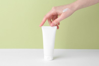 Photo of Woman with tube of cream on color background, closeup