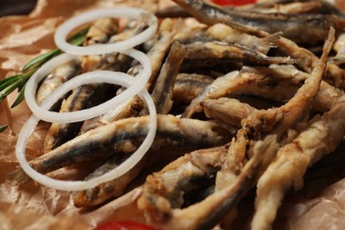 Photo of Delicious fried anchovies with onion rings served on table, closeup