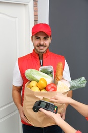 Woman using terminal to pay for food delivery indoors