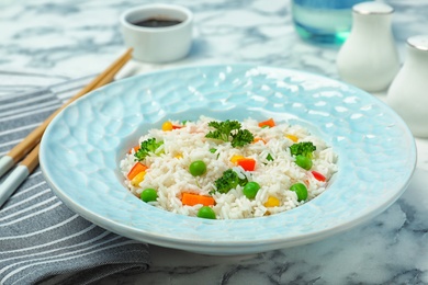 Photo of Plate of boiled rice with vegetables on table