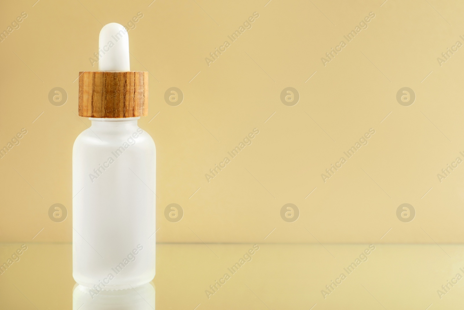 Photo of Bottle of face serum on beige background, closeup. Space for text