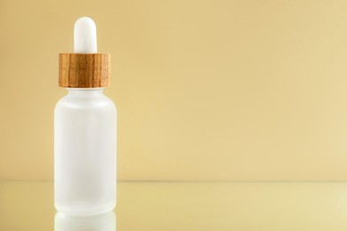 Photo of Bottle of face serum on beige background, closeup. Space for text
