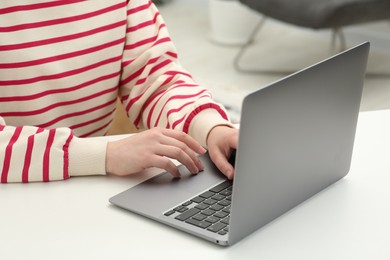 Photo of Woman using laptop at white table indoors, closeup