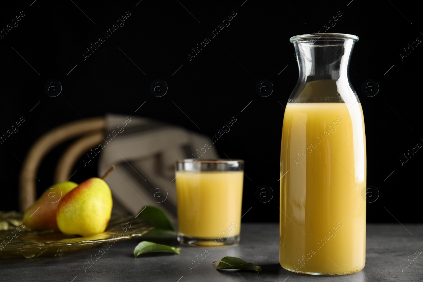 Photo of Fresh pear juice in glass bottle on grey table