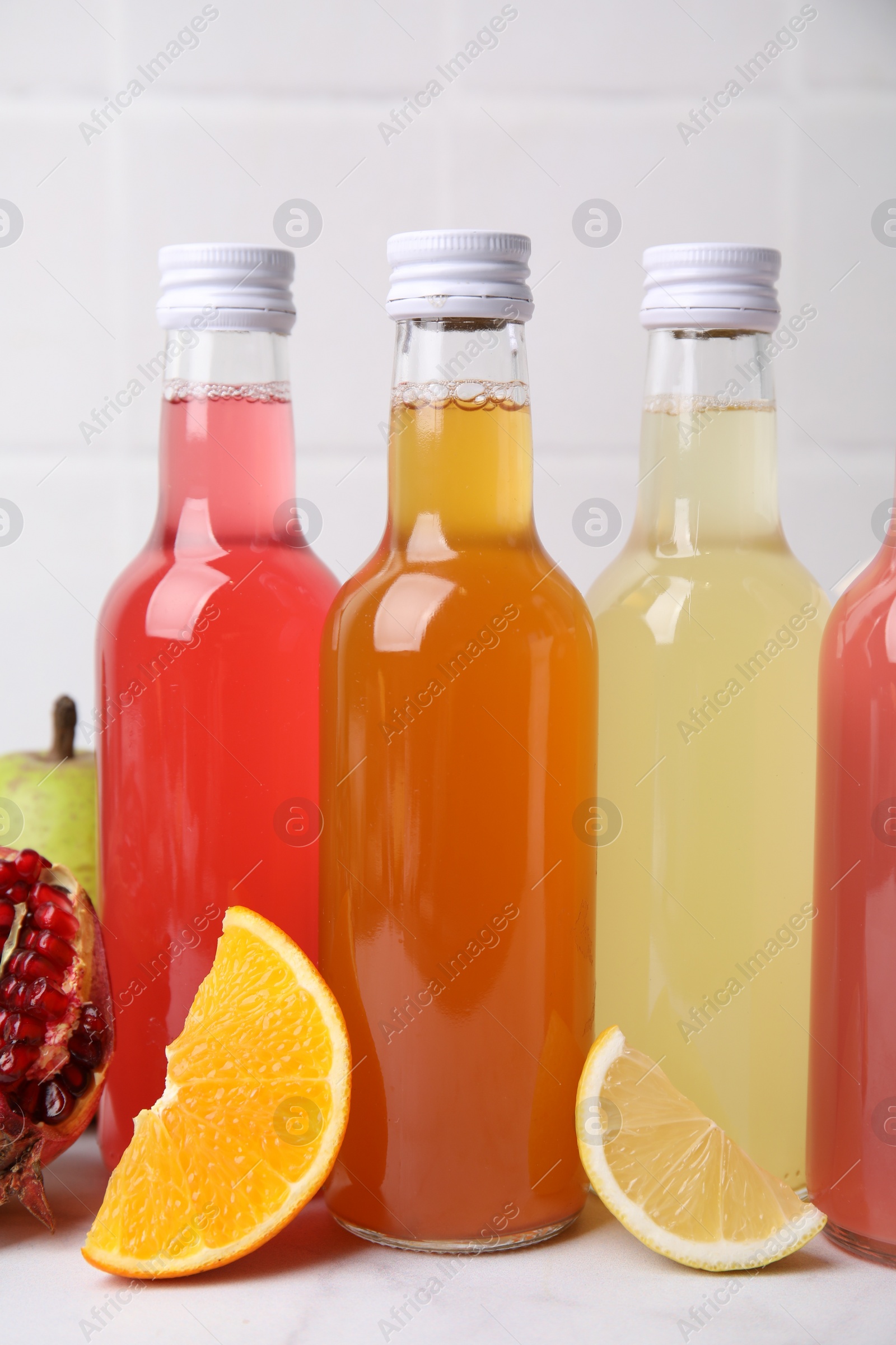 Photo of Delicious kombucha in glass bottles and fresh fruits on white table