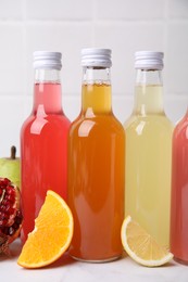 Delicious kombucha in glass bottles and fresh fruits on white table