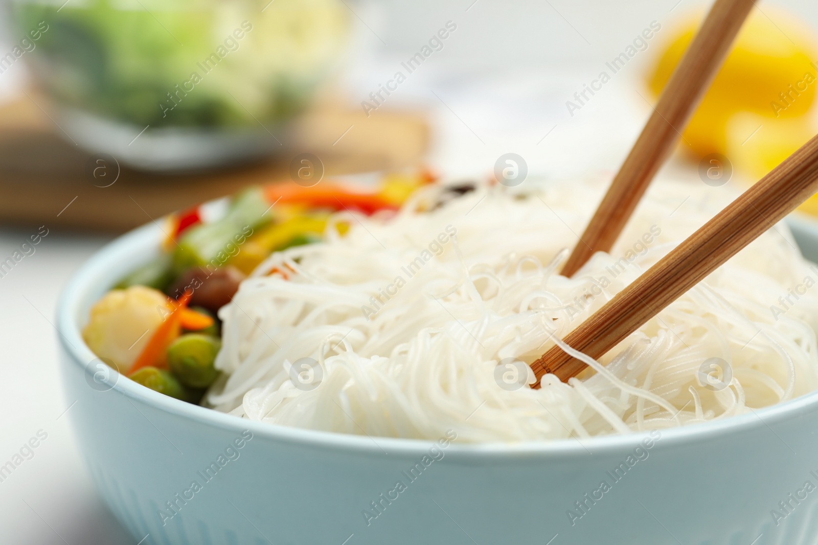 Photo of Tasty cooked rice noodles with vegetables in bowl, closeup
