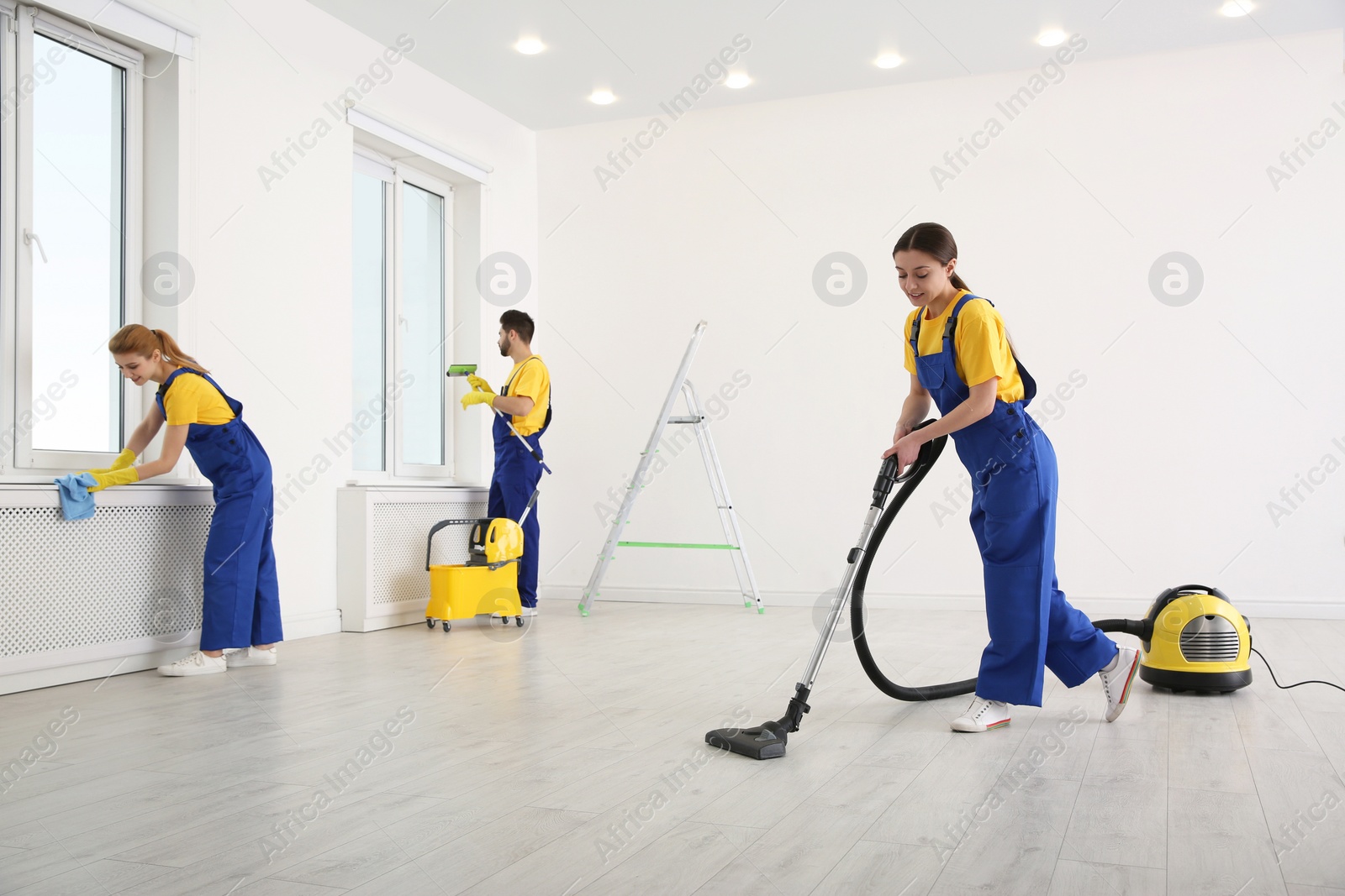 Photo of Team of professional janitors in uniforms cleaning room