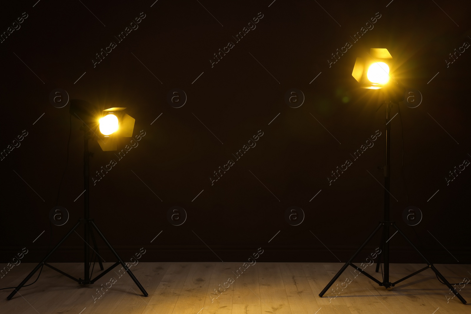 Photo of Bright spotlights near wall in dark room, space for text