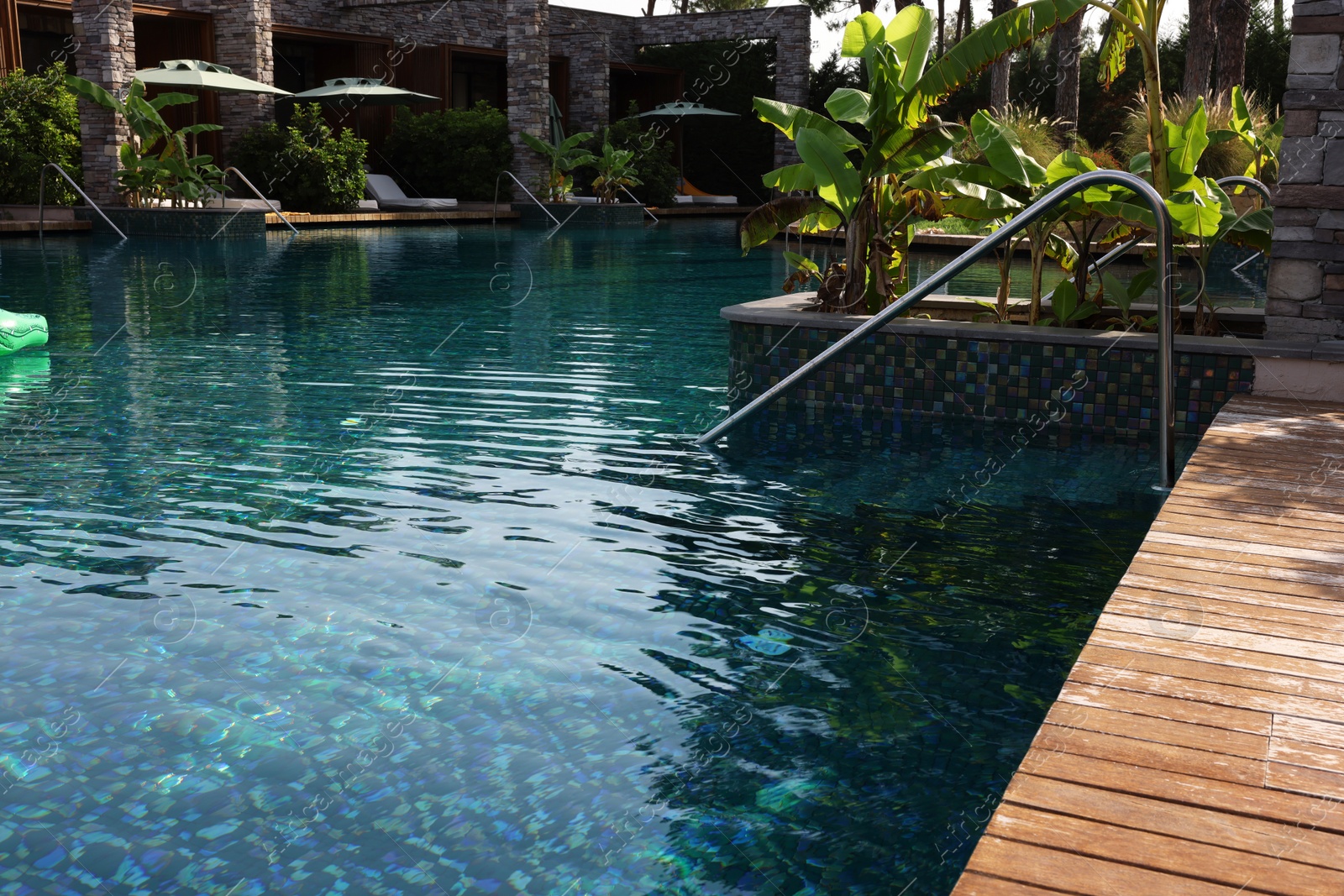 Photo of Swimming pool, metal rail and tropical plants at luxury resort