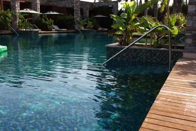 Swimming pool, metal rail and tropical plants at luxury resort