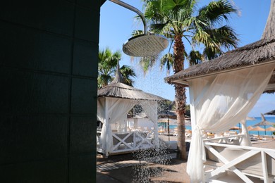 Photo of Outdoor shower with running water on beach at resort