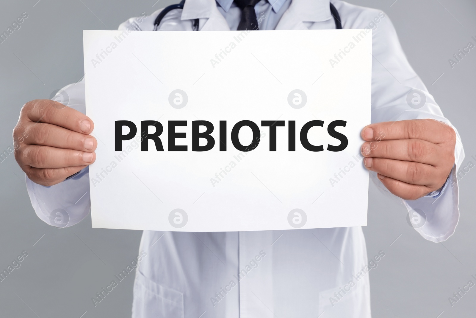 Image of Doctor holding paper with word PREBIOTICS on light grey background, closeup