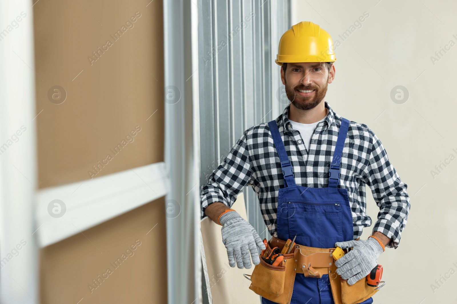 Photo of Professional builder in uniform with tool belt indoors