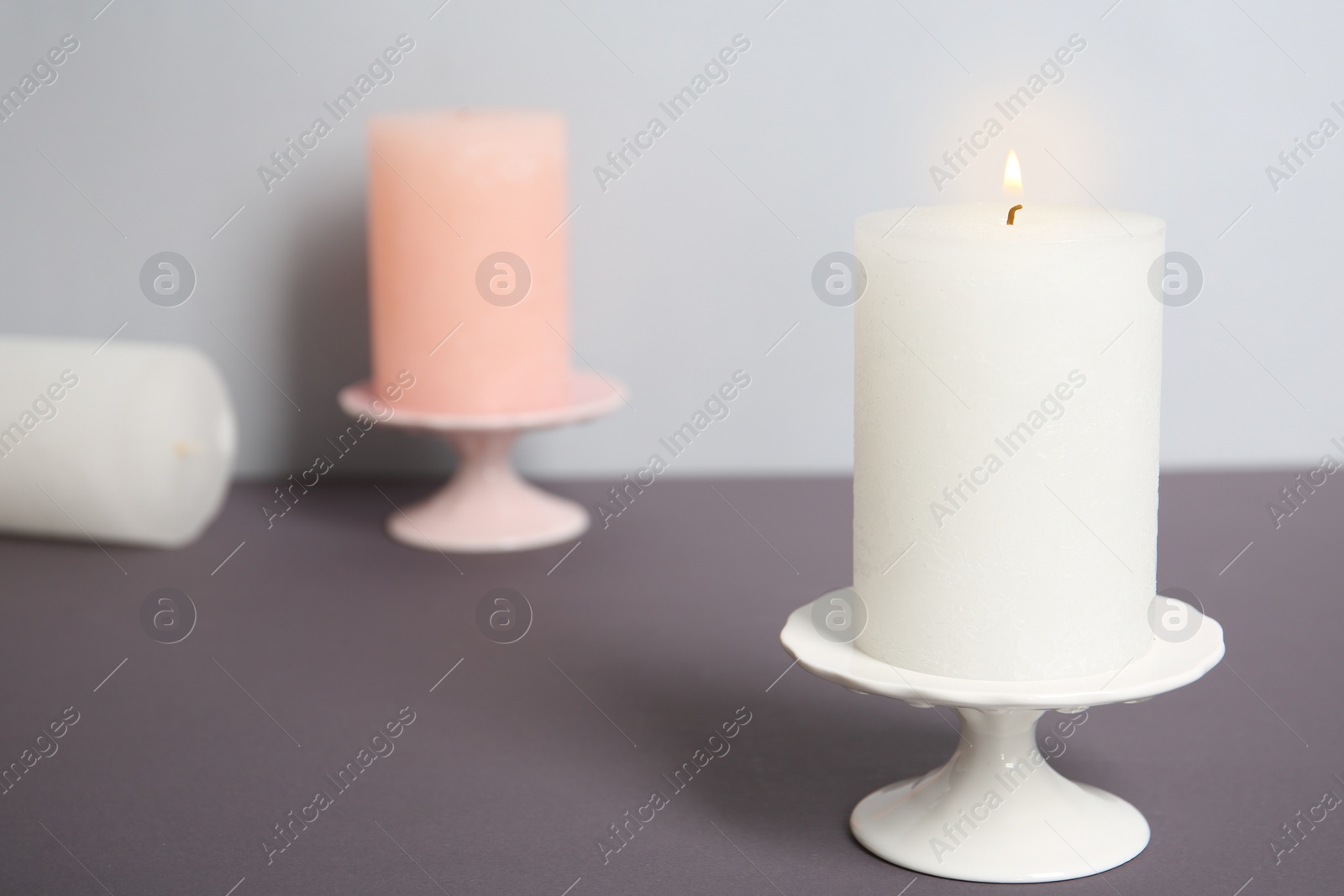 Photo of Decorative wax candles on table against light background