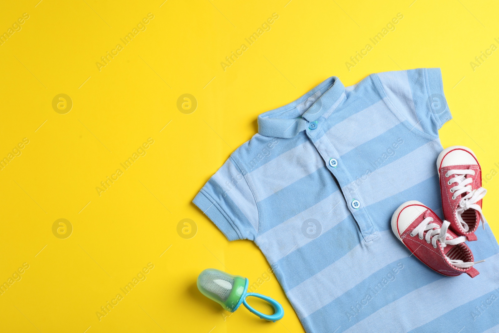 Photo of Flat lay composition with bodysuit and space for text on color background. Baby accessories