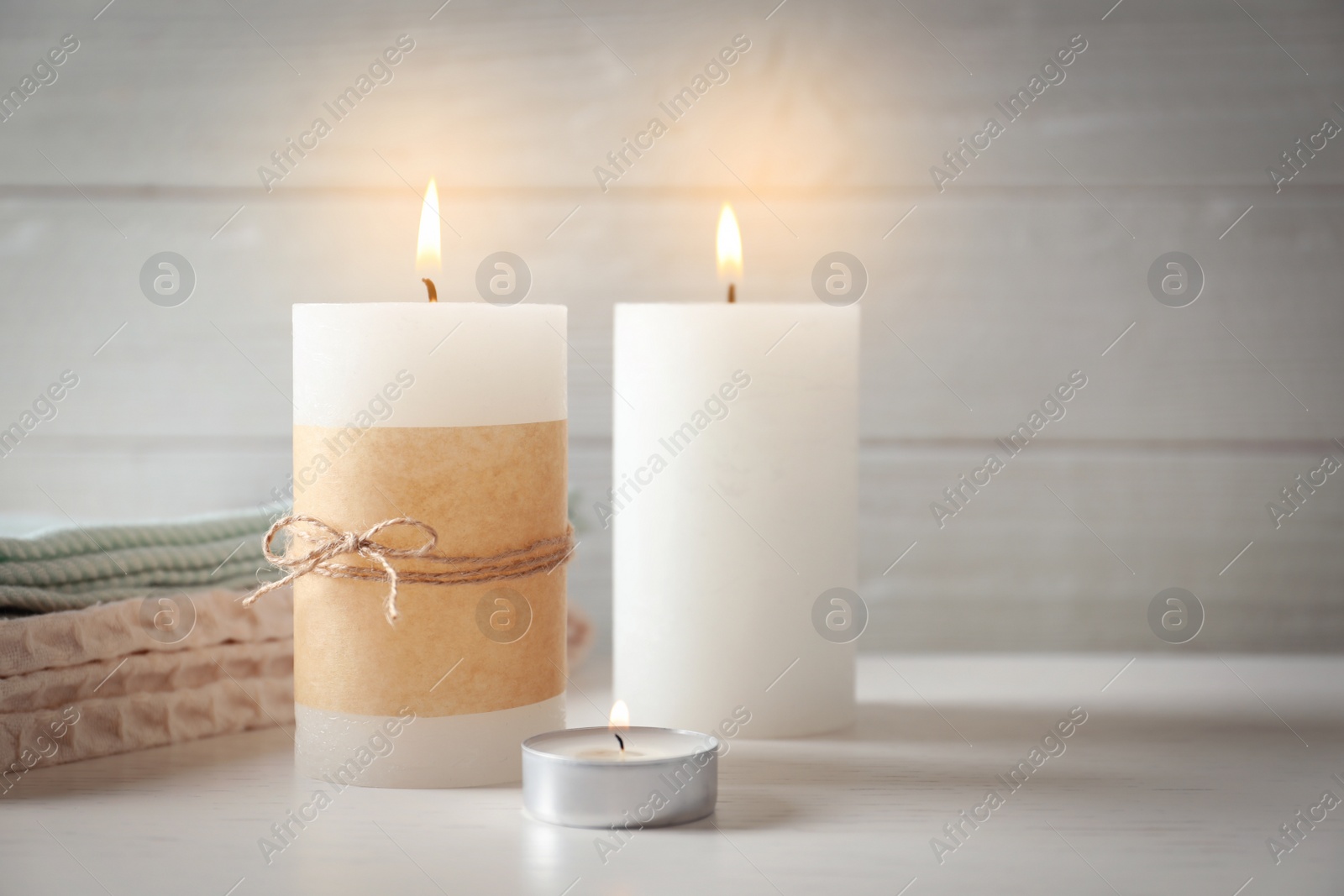 Photo of Burning wax candles of different shapes on table