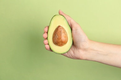 Photo of Woman holding ripe cut avocado on color background