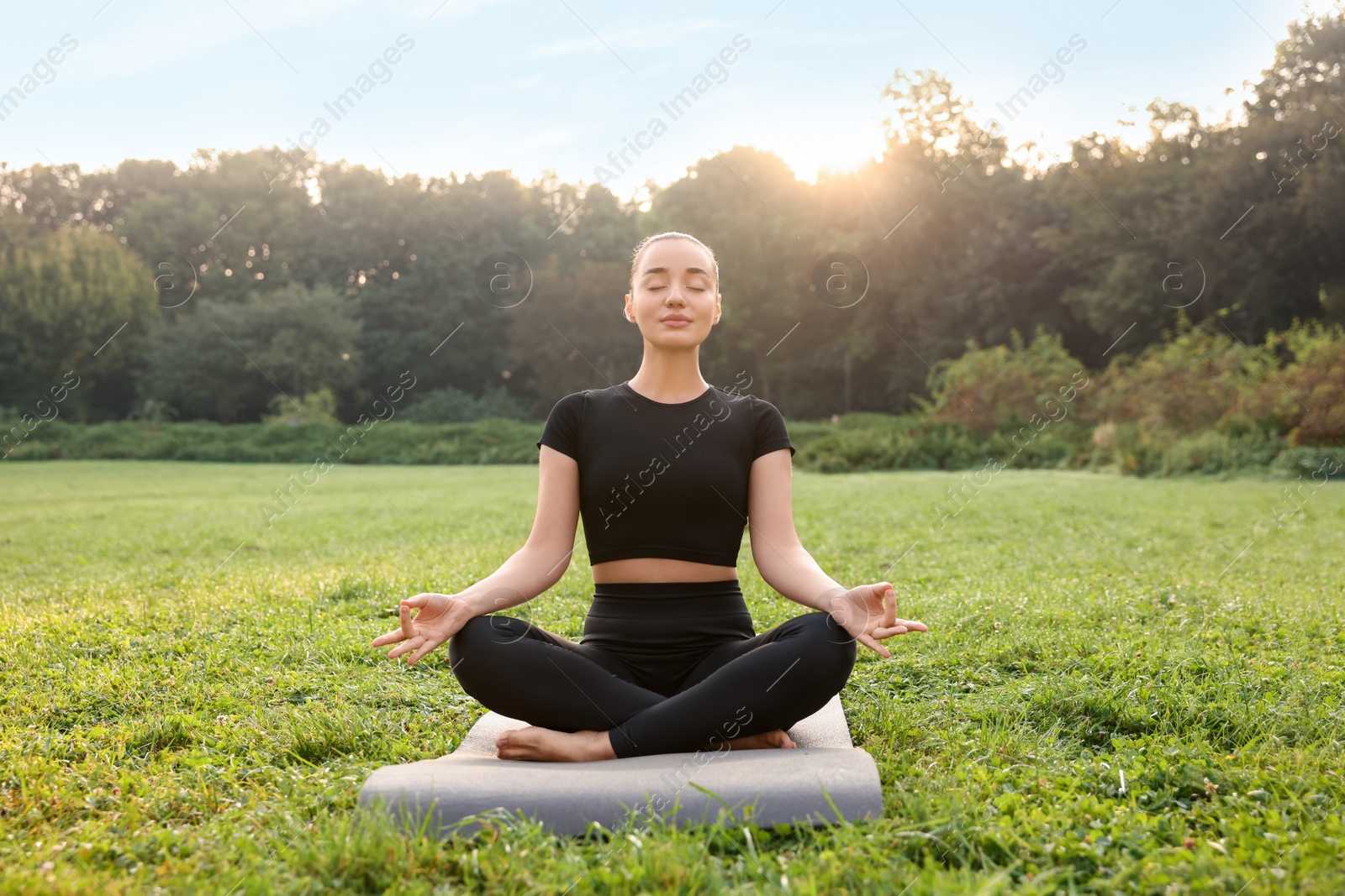 Photo of Beautiful woman practicing yoga outdoors on sunny day. Lotus pose