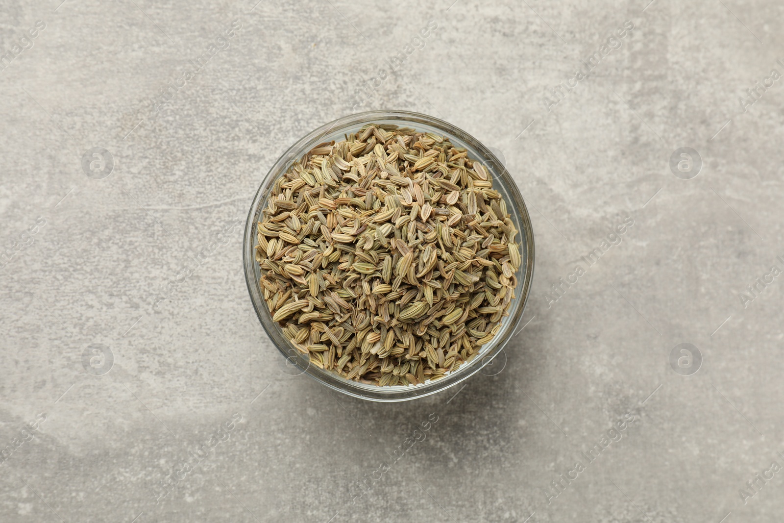 Photo of Fennel seeds in bowl on grey table, top view