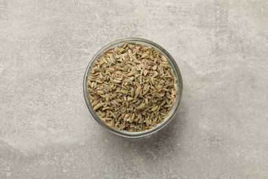 Fennel seeds in bowl on grey table, top view