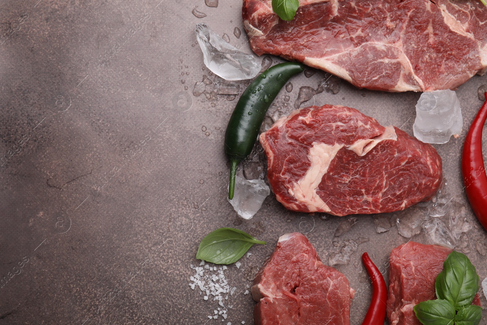 Photo of Flat lay composition with cut fresh beef meat on brown table. Space for text