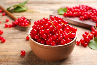 Photo of Delicious red currants in bowl on wooden table