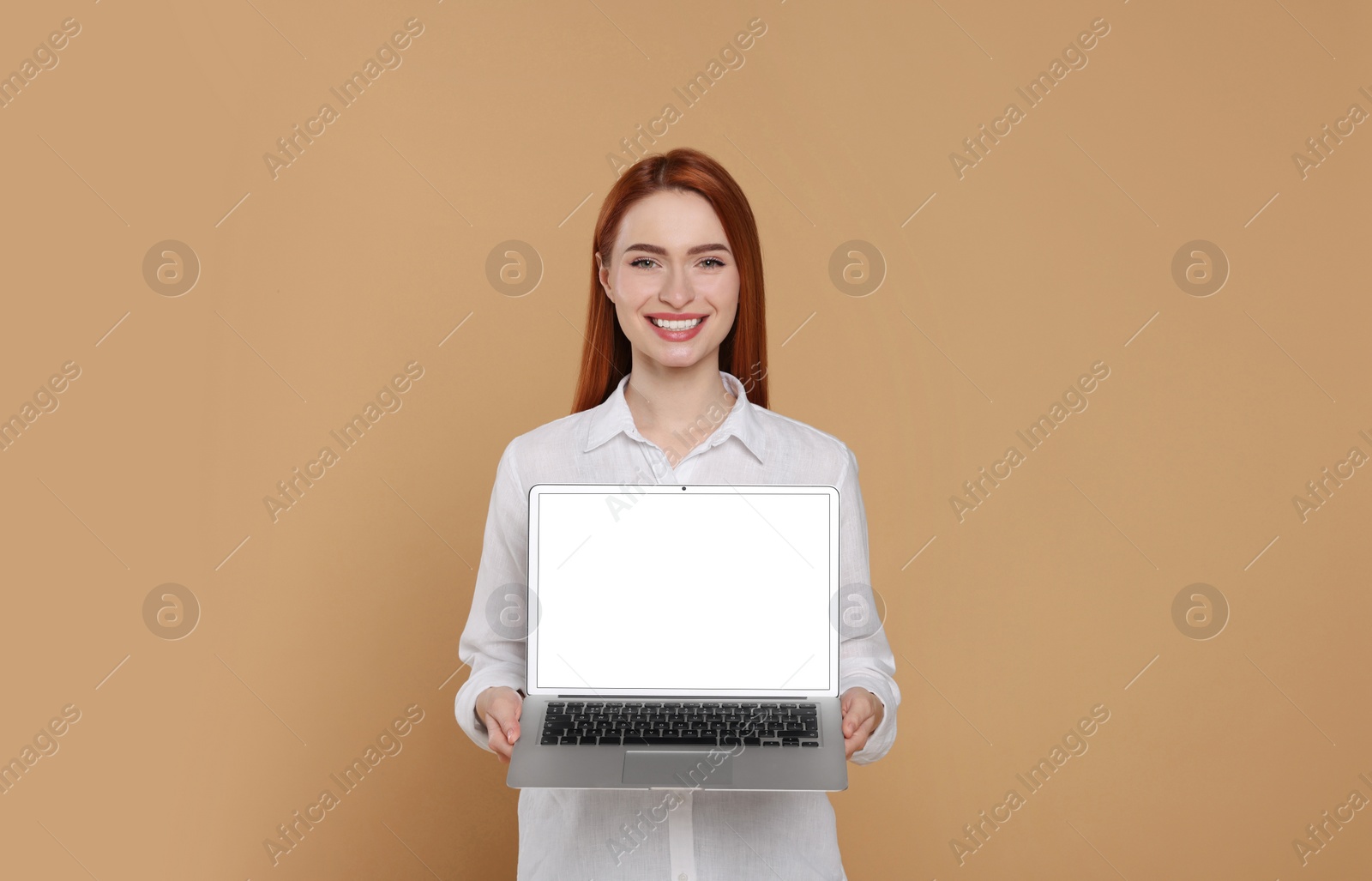 Photo of Smiling young woman showing laptop on beige background