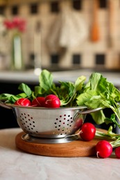 Photo of Metal colander with fresh radishes on white table