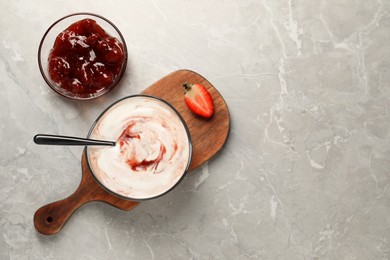 Photo of Tasty yoghurt with jam and strawberry on grey table, flat lay. Space for text