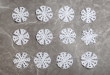 Photo of Many paper snowflakes on grey background, flat lay