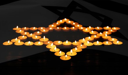Image of Holocaust memory day, banner design. Double exposure with star of David made with burning candles and flag of Israel