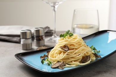 Delicious pasta with truffle slices and microgreens served on light grey table, space for text