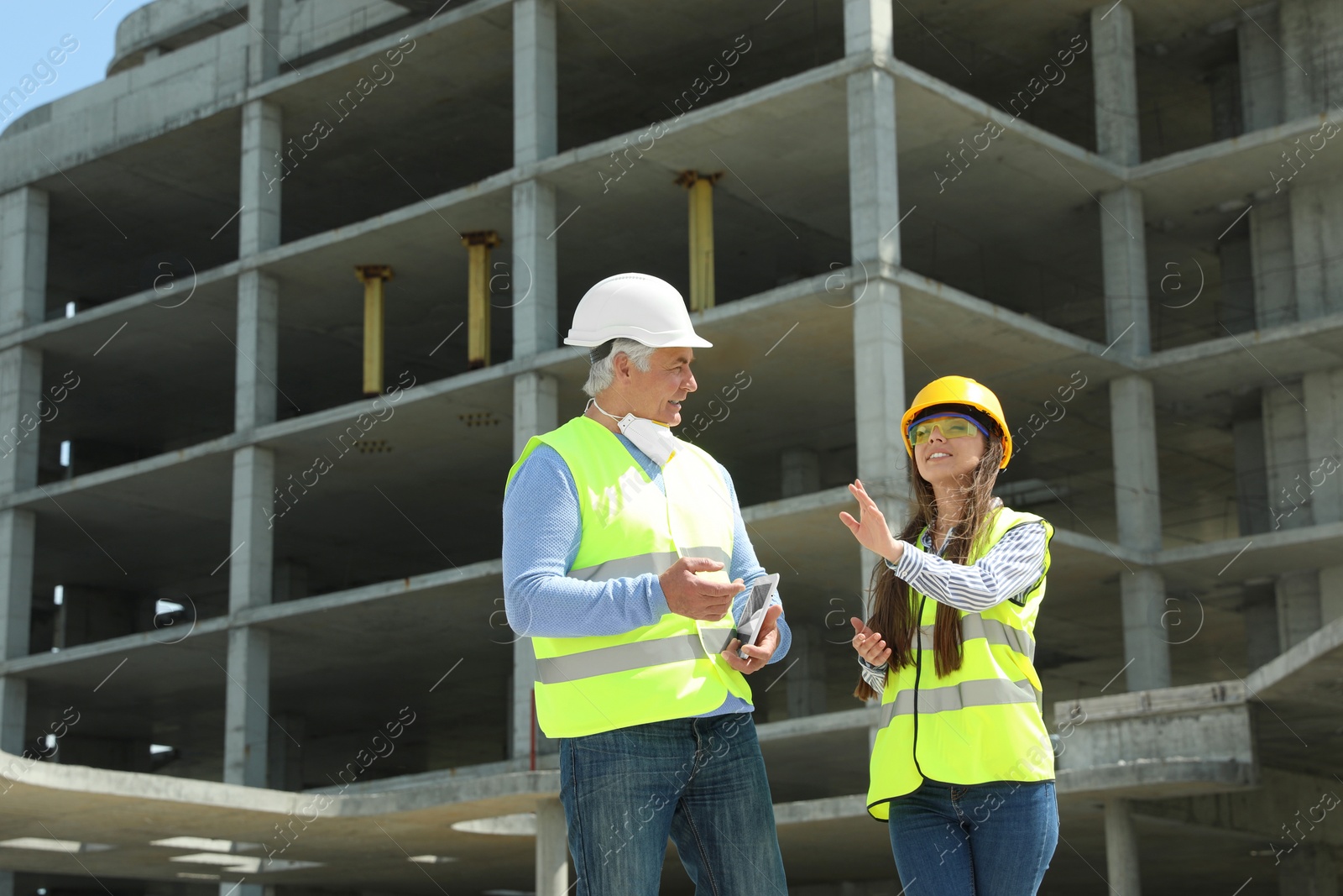 Photo of Professional engineer and foreman with tablet in safety equipment at construction site. Space for text.