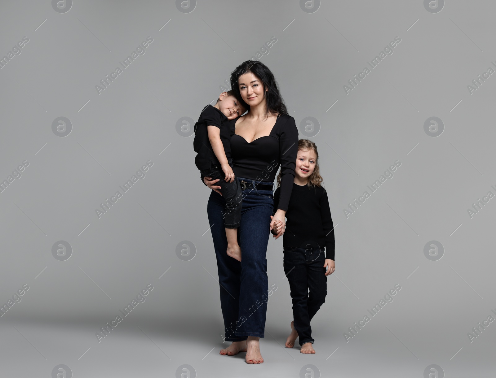 Photo of Little children with their mother on grey background