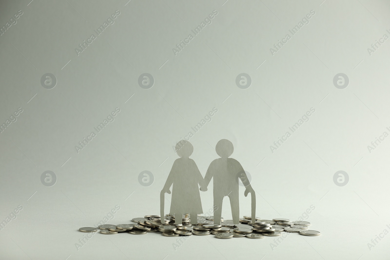 Photo of Pension savings. Figure of senior couple and coins on grey background