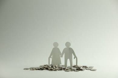 Pension savings. Figure of senior couple and coins on grey background