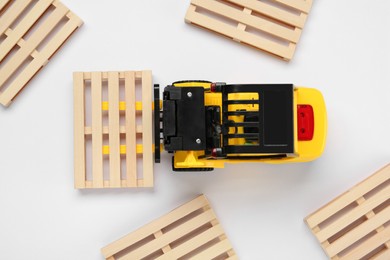 Photo of Toy forklift and wooden pallets on white background, top view