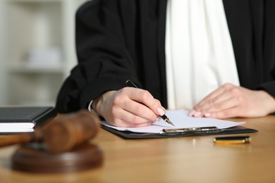Photo of Judge working with document at table indoors, closeup