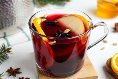 Photo of Delicious mulled wine on white wooden table, closeup
