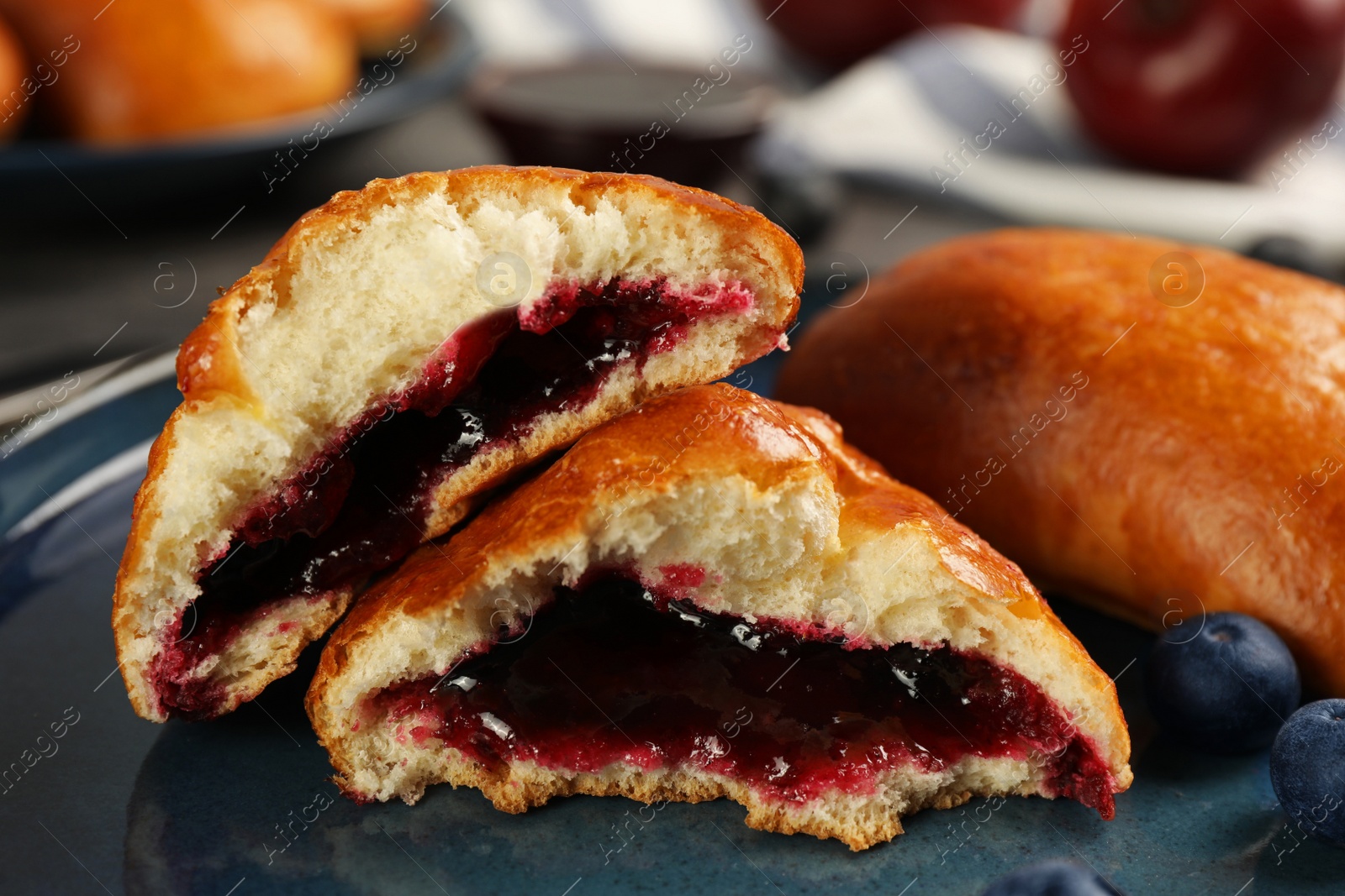 Photo of Delicious baked patties with jam and blueberries on plate, closeup