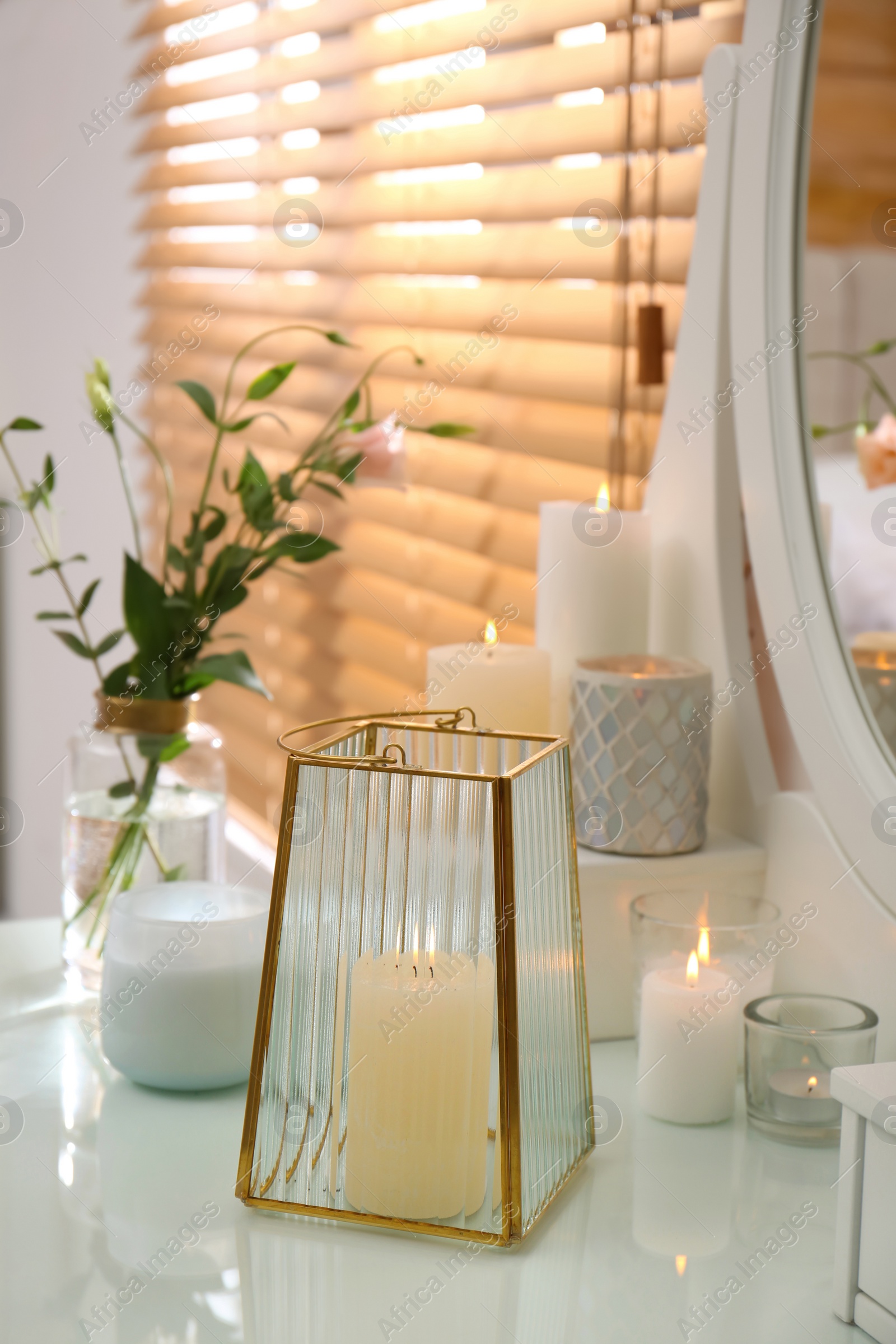 Photo of Burning scented candles and bouquet on dressing table indoors