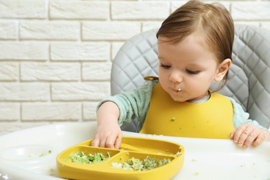 Photo of Cute little baby eating healthy food in high chair indoors. Space for text
