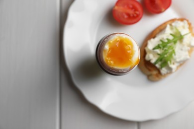 Photo of Breakfast with soft boiled egg on white wooden table, top view. Space for text