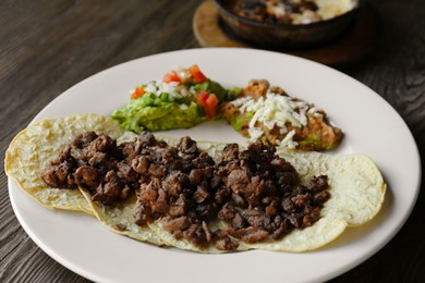 Plate with delicious tacos served on wooden table