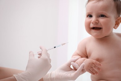 Photo of Doctor vaccinating baby against light background. Health care