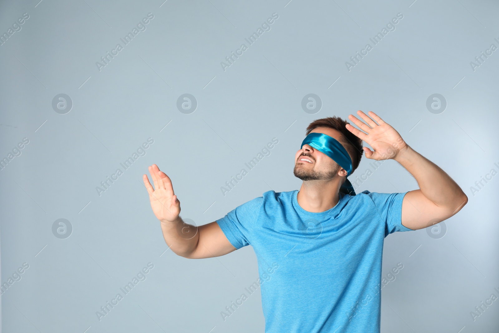 Photo of Young man with light blue blindfold on grey background