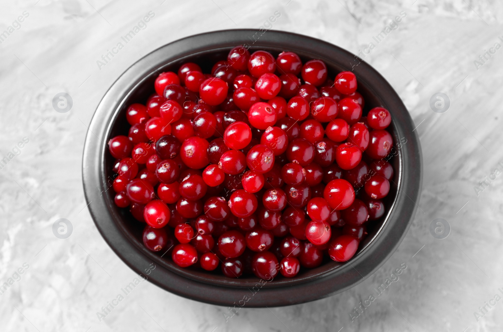 Photo of Fresh ripe cranberries in bowl on grey table, top view