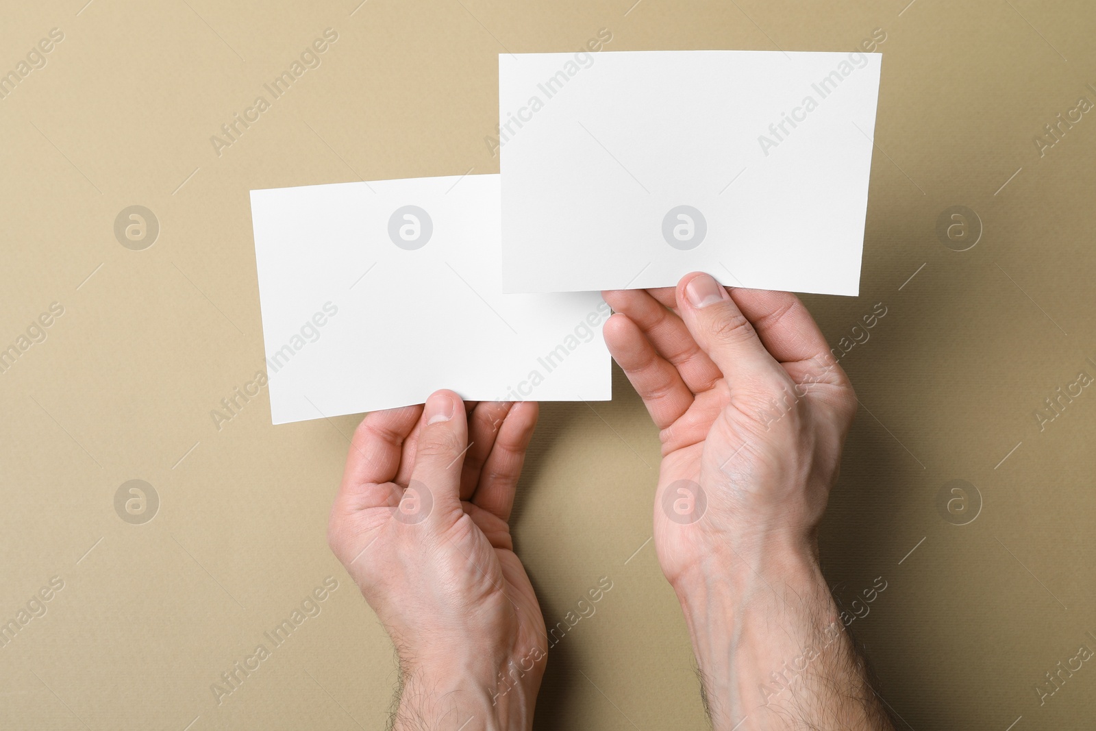 Photo of Man holding flyers on light brown background, top view. Mockup for design